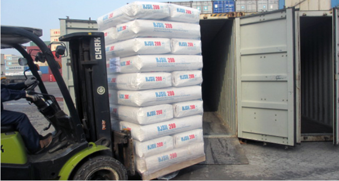 Forklift loading bags of silica into a shipping container.